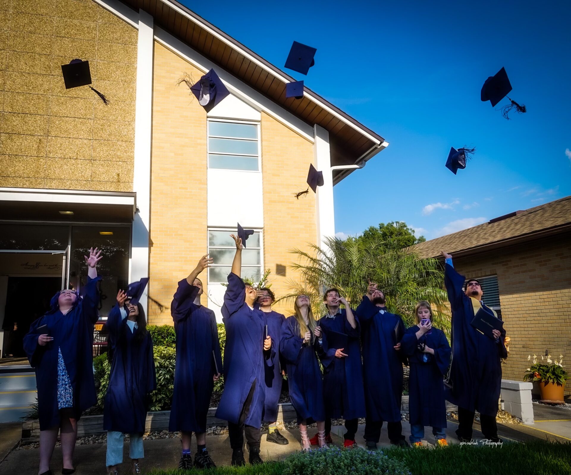 A group of multi-ethnic teenagers are throwing their graduation caps into the air.